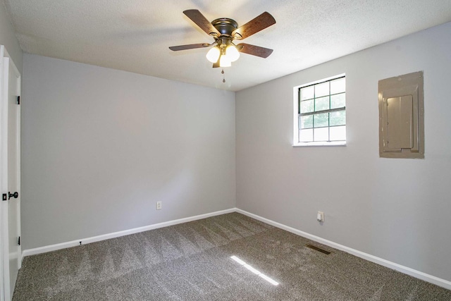 carpeted spare room with visible vents, a ceiling fan, a textured ceiling, electric panel, and baseboards