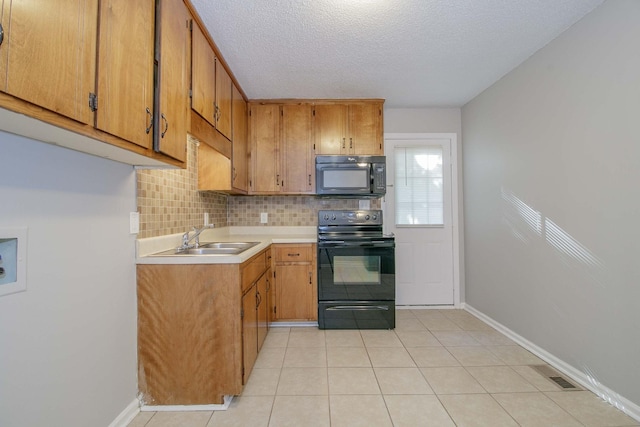 kitchen featuring brown cabinets, a sink, light countertops, black appliances, and backsplash