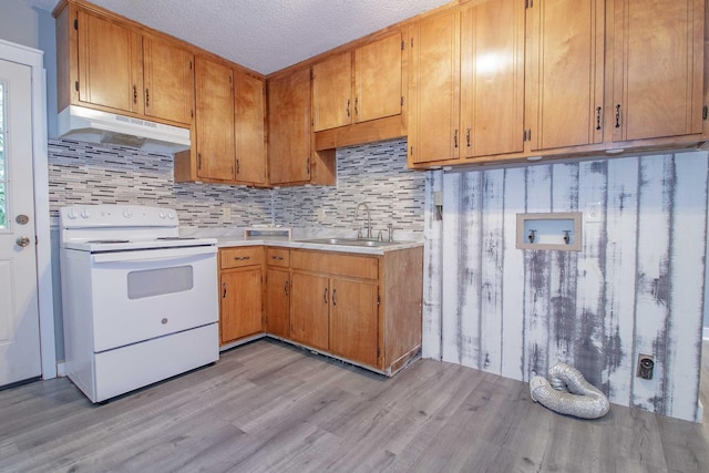 kitchen featuring white electric range oven, light countertops, light wood-type flooring, under cabinet range hood, and a sink