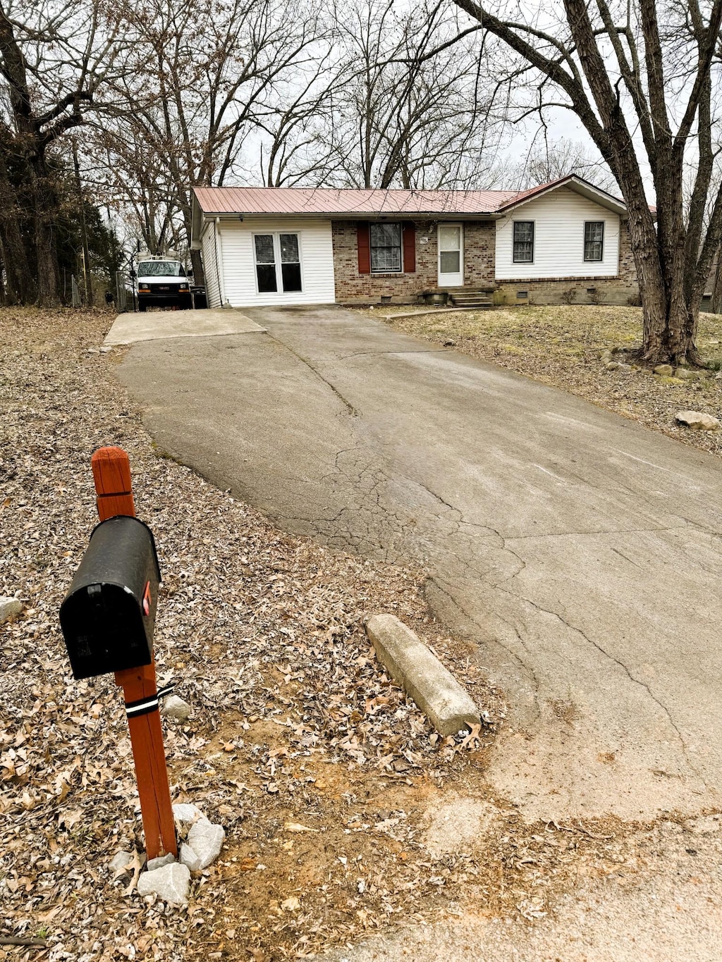 ranch-style house with metal roof and driveway