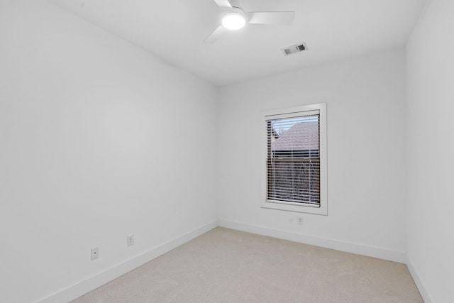 spare room with light carpet, a ceiling fan, visible vents, and baseboards