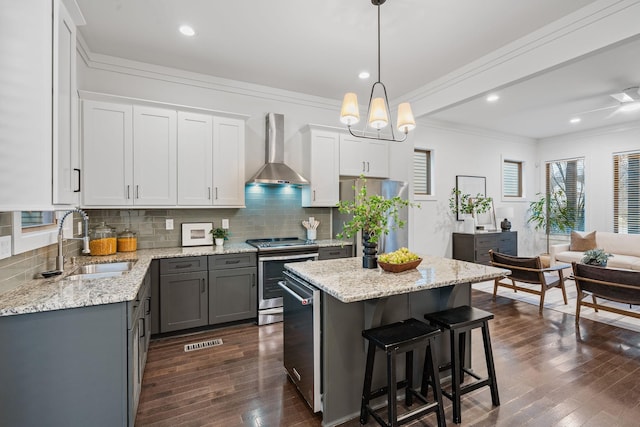 kitchen featuring decorative backsplash, dark wood-style floors, wall chimney exhaust hood, stainless steel appliances, and a sink