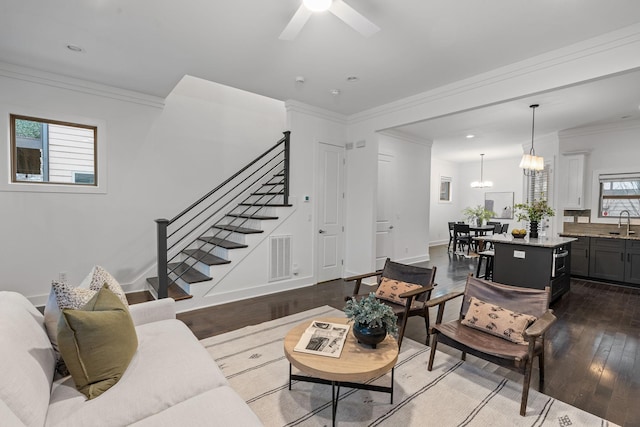 living room with baseboards, visible vents, hardwood / wood-style flooring, stairs, and crown molding