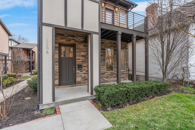 property entrance featuring a balcony and stone siding