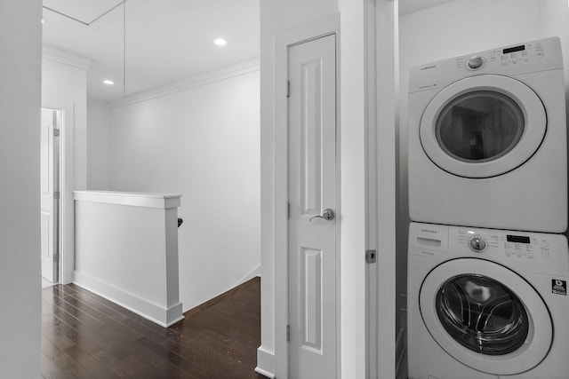 washroom featuring dark wood finished floors, ornamental molding, stacked washer / dryer, attic access, and baseboards