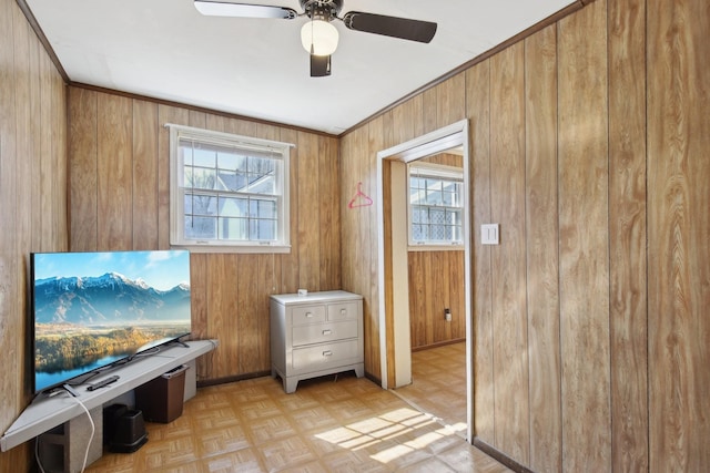 interior space with crown molding, wood walls, and a healthy amount of sunlight