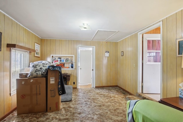 carpeted bedroom featuring attic access, wooden walls, and baseboards