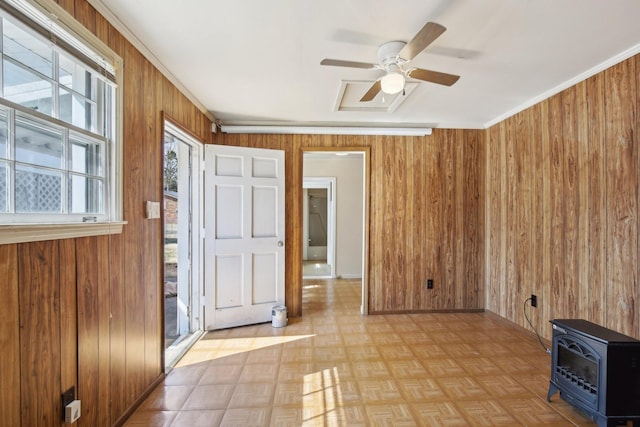 interior space featuring a ceiling fan, ornamental molding, heating unit, a wood stove, and wood walls