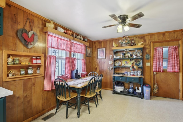 dining area with ceiling fan, wooden walls, visible vents, and carpet flooring