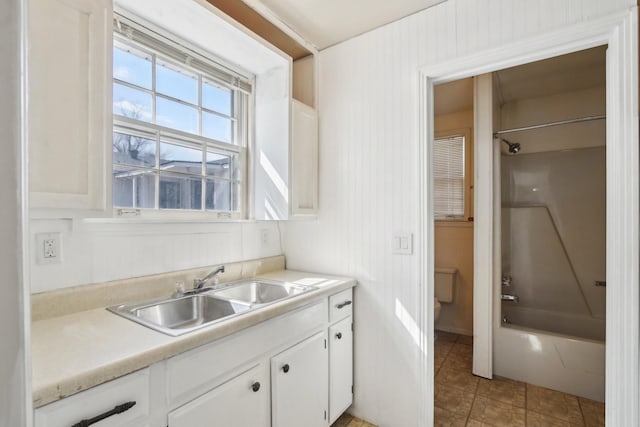 kitchen featuring light countertops, white cabinets, and a sink