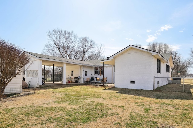 back of house featuring crawl space, fence, a lawn, and brick siding