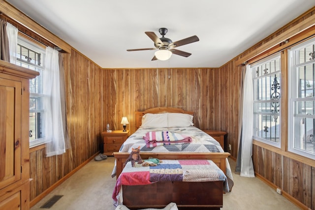 bedroom with multiple windows, wood walls, visible vents, and light colored carpet