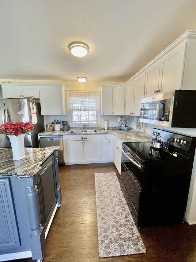 kitchen featuring light stone counters, dark wood-style flooring, appliances with stainless steel finishes, white cabinetry, and a sink