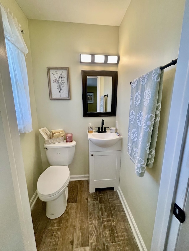 bathroom featuring toilet, wood finished floors, vanity, and baseboards