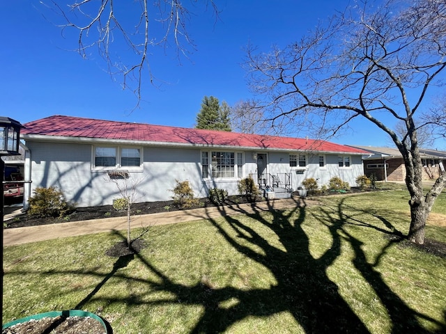 view of front of home featuring metal roof, brick siding, and a front lawn