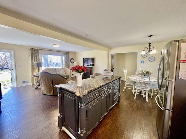 kitchen with visible vents, dark wood-type flooring, freestanding refrigerator, and light stone countertops