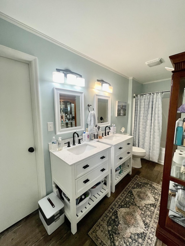 bathroom with toilet, wood finished floors, vanity, visible vents, and crown molding