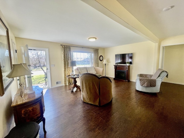 living area featuring a healthy amount of sunlight, a fireplace, visible vents, and dark wood-style flooring