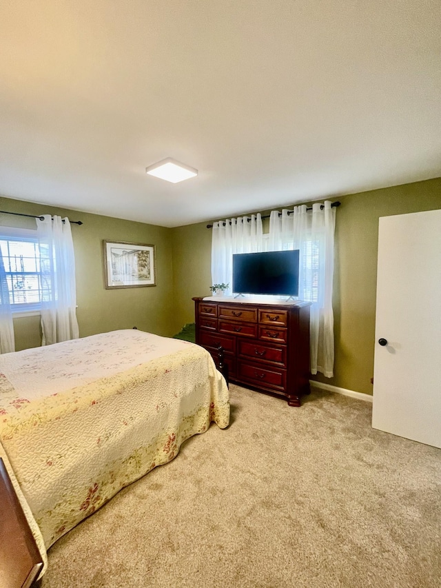 bedroom with baseboards and light colored carpet