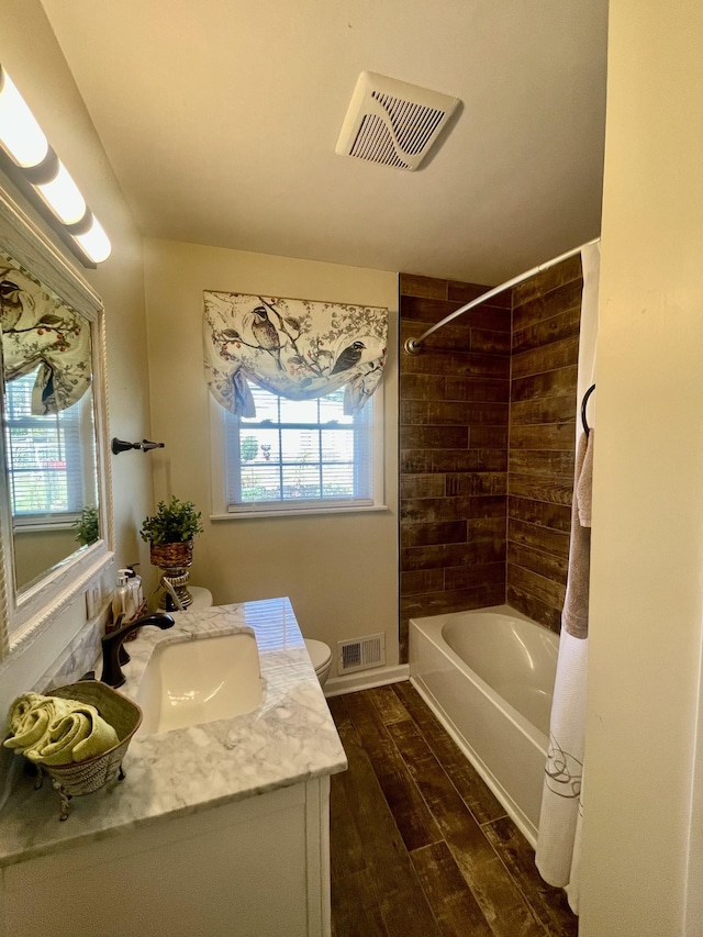 full bath with a wealth of natural light, visible vents, and wood finished floors