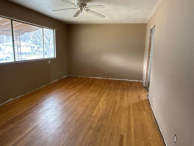 spare room with a ceiling fan, a textured ceiling, and wood finished floors