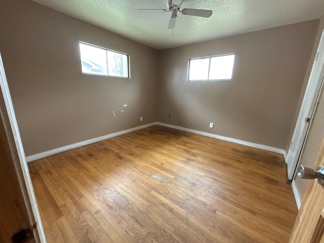 unfurnished room featuring baseboards, ceiling fan, a textured ceiling, and light wood finished floors