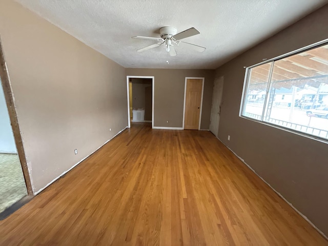 unfurnished bedroom with a textured ceiling, light wood finished floors, and a ceiling fan