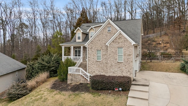 view of front of home featuring driveway, a shingled roof, stairway, fence, and brick siding