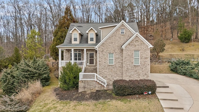 view of front of home featuring a porch, brick siding, stairway, and roof with shingles