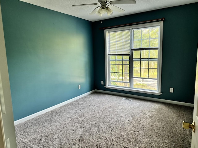 spare room with a healthy amount of sunlight, baseboards, visible vents, and carpet flooring