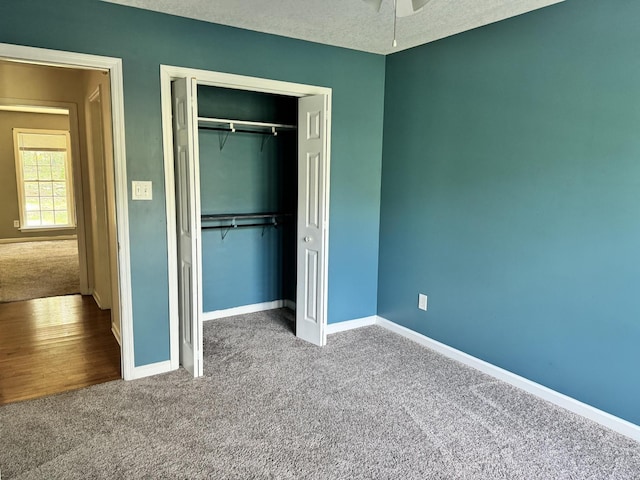 unfurnished bedroom featuring a textured ceiling, a closet, carpet, and baseboards