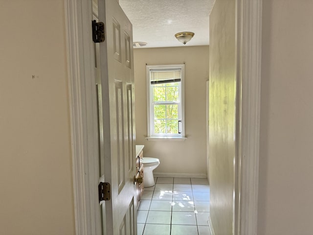 bathroom featuring a textured ceiling, baseboards, toilet, and tile patterned floors