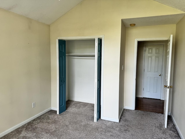 unfurnished bedroom featuring carpet floors, a closet, vaulted ceiling, and baseboards