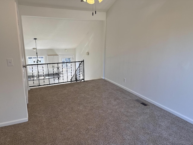 unfurnished room with ceiling fan with notable chandelier, carpet, visible vents, and baseboards