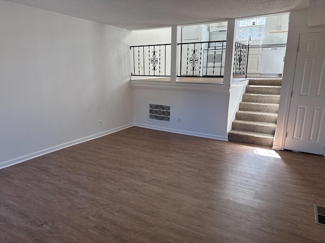 empty room featuring baseboards, visible vents, dark wood-style flooring, stairs, and a sink