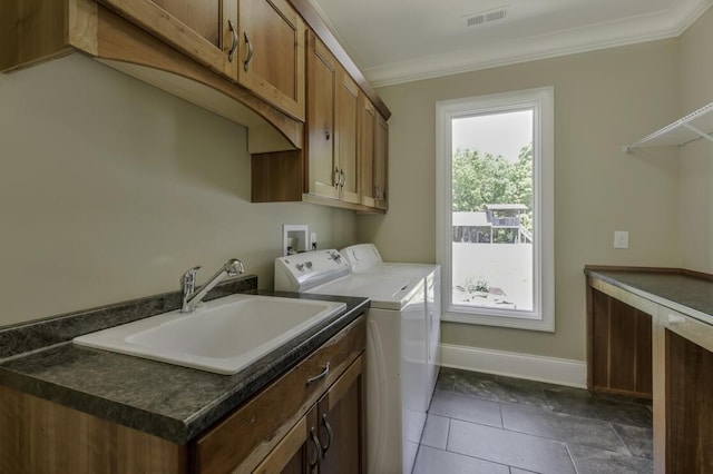 washroom with cabinet space, visible vents, crown molding, washer and dryer, and a sink