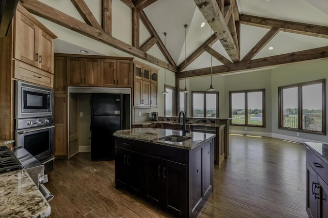 kitchen with dark wood finished floors, stainless steel appliances, a sink, light stone countertops, and a peninsula