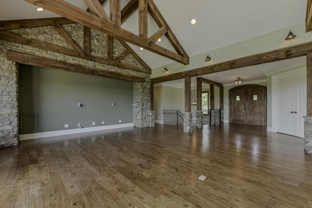 unfurnished living room with baseboards, arched walkways, wood finished floors, beamed ceiling, and high vaulted ceiling