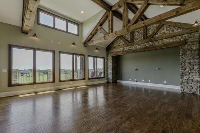 interior space with a healthy amount of sunlight, beam ceiling, and wood finished floors