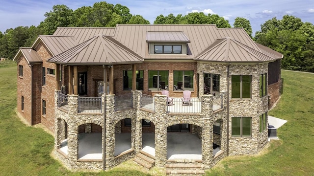 view of front facade with a standing seam roof, brick siding, a patio, and a front yard