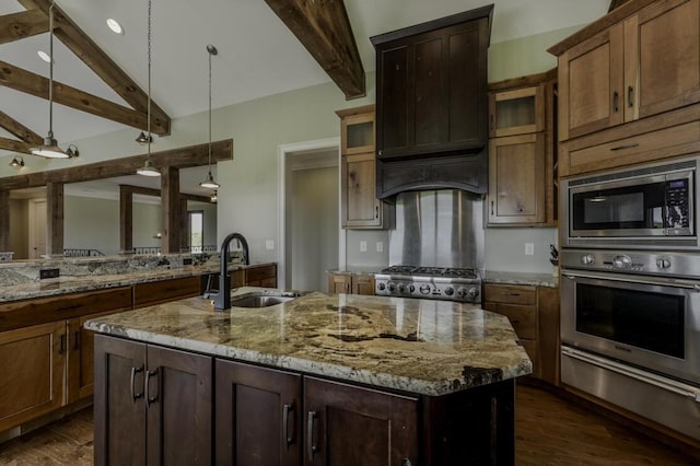 kitchen featuring an island with sink, lofted ceiling with beams, stainless steel appliances, pendant lighting, and a sink