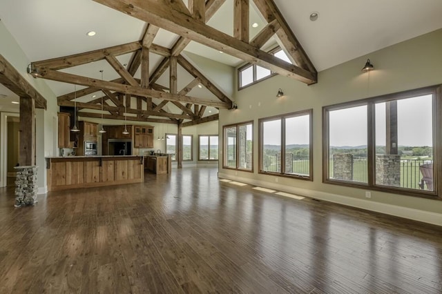 unfurnished living room featuring dark wood-style flooring, a healthy amount of sunlight, and baseboards