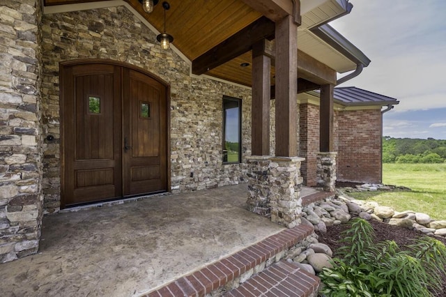 entrance to property with stone siding, brick siding, and metal roof