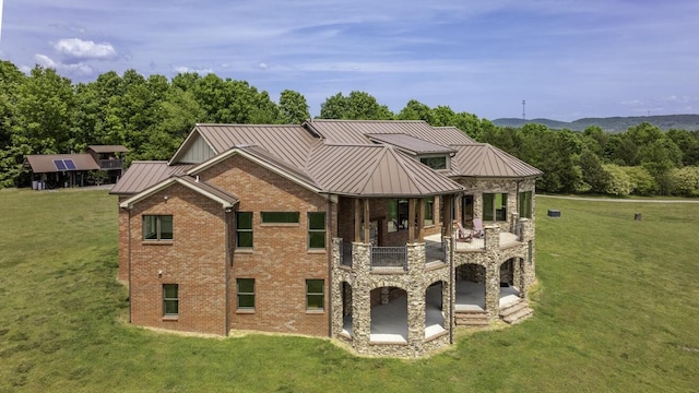 view of front of home featuring metal roof, brick siding, stone siding, a front lawn, and a standing seam roof