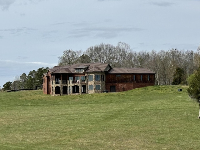 back of property featuring metal roof, a yard, a standing seam roof, and stone siding