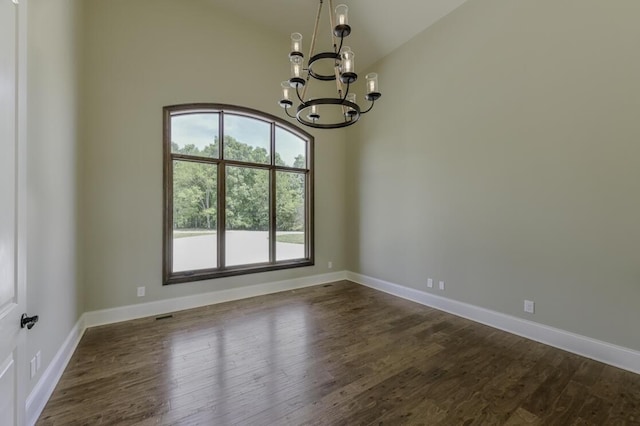 spare room with a chandelier, vaulted ceiling, dark wood-style floors, and baseboards