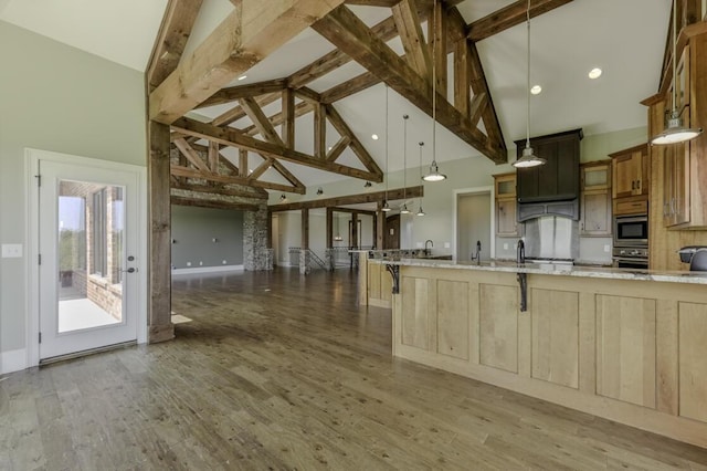 kitchen with light stone counters, stainless steel appliances, glass insert cabinets, wood finished floors, and a kitchen bar