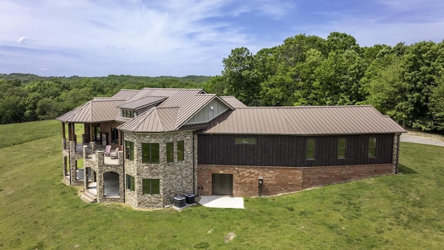 exterior space featuring metal roof, central AC unit, brick siding, a yard, and a standing seam roof