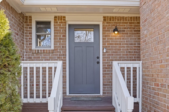 entrance to property featuring brick siding and visible vents