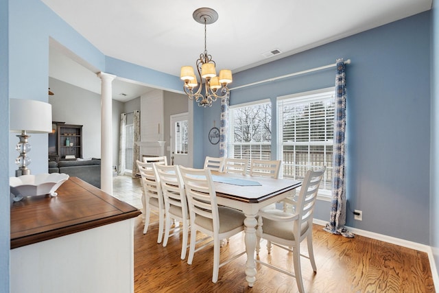 dining area featuring decorative columns, a notable chandelier, visible vents, light wood-style floors, and baseboards